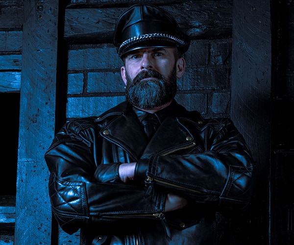 Man in a leather peaked cap and jacket, arms crossed
