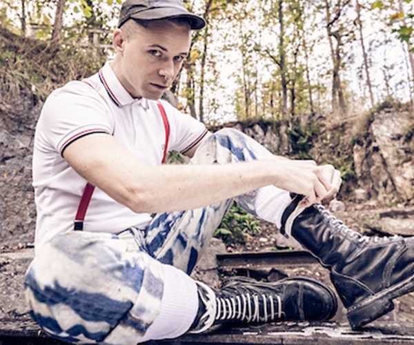 Man in skinhead style: cropped hair, braces, polo shirt, and laced boots