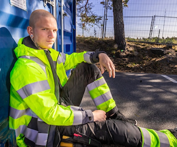 Man in high-visibility workwear seated roadside
